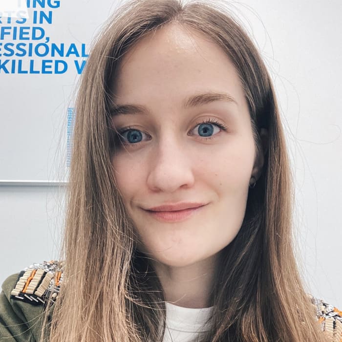 A young woman with light brown hair smiles at the camera