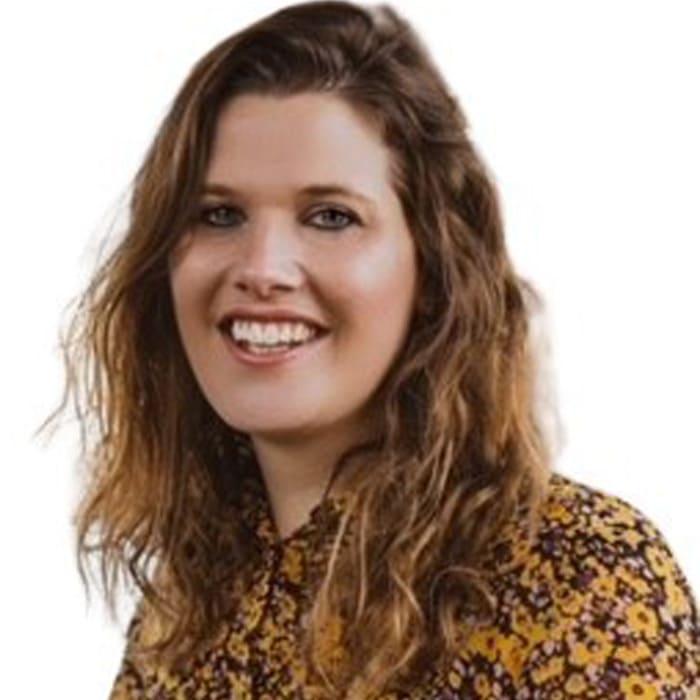 A woman with brown wavy hair smiles at the camera